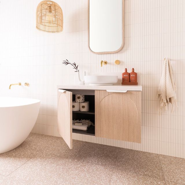 ADP Archie wall hung vanity with Caesarstone top in light woodgrain, shown in a bathroom setting with open door storage and basin
