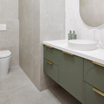 ADP Archie wall hung vanity in green with white Caesarstone top, curved front and brass handles in a bathroom