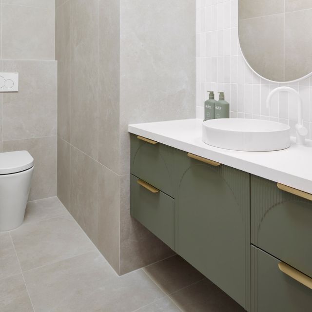 ADP Archie wall hung vanity in green with white Caesarstone top, curved front and brass handles in a bathroom
