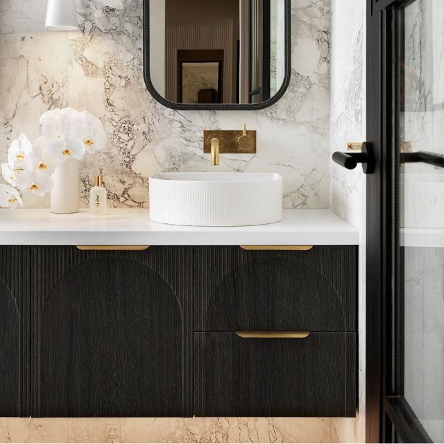 ADP Archie wall hung vanity in dark woodgrain with white top, arched front detail and gold handles in bathroom setting