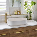 Phoenix Cromford vessel mixer in brushed gold, shown beside an above-counter basin on a vanity