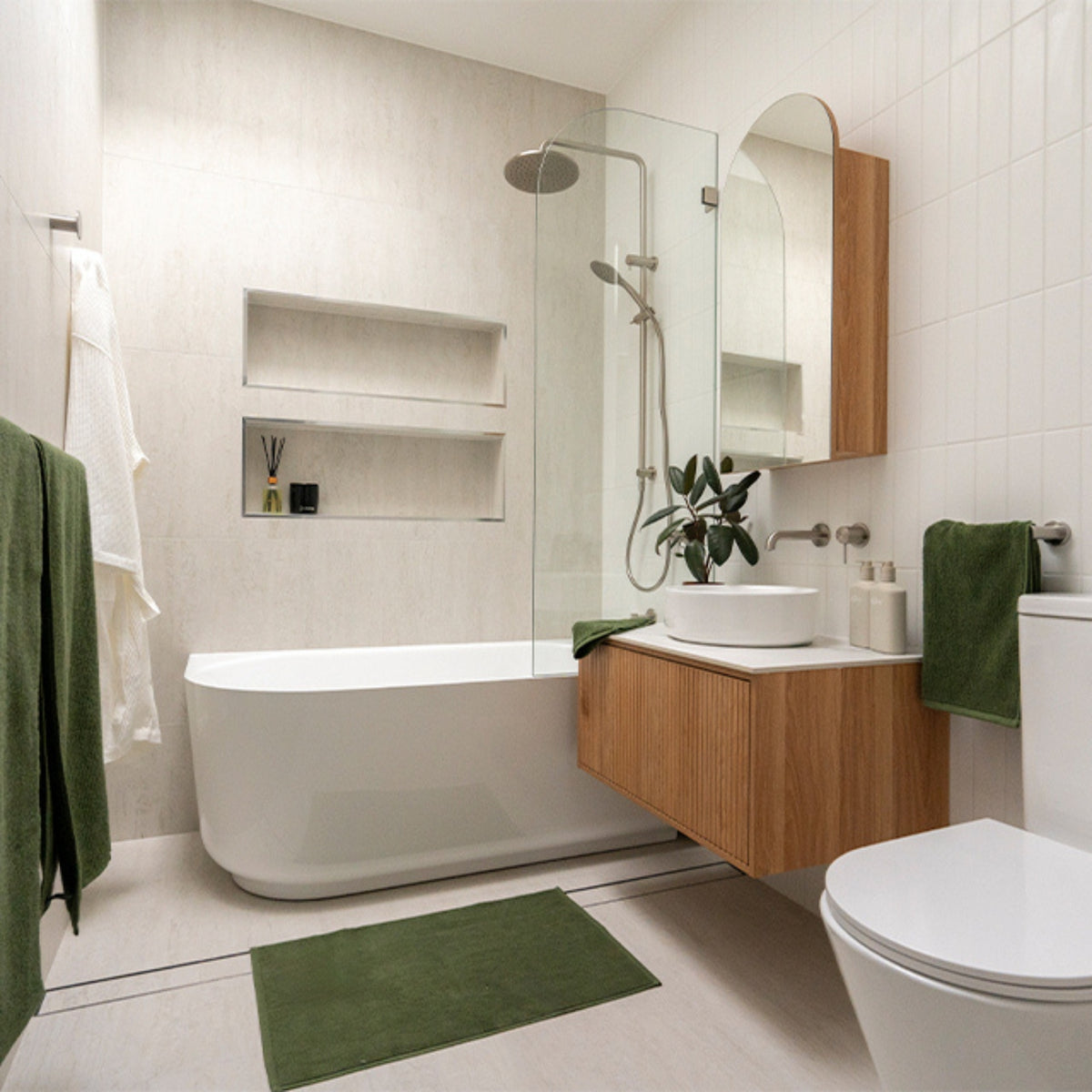 Brushed nickel hand towel rail beside a bathroom vanity in a modern white and timber bathroom with green towels