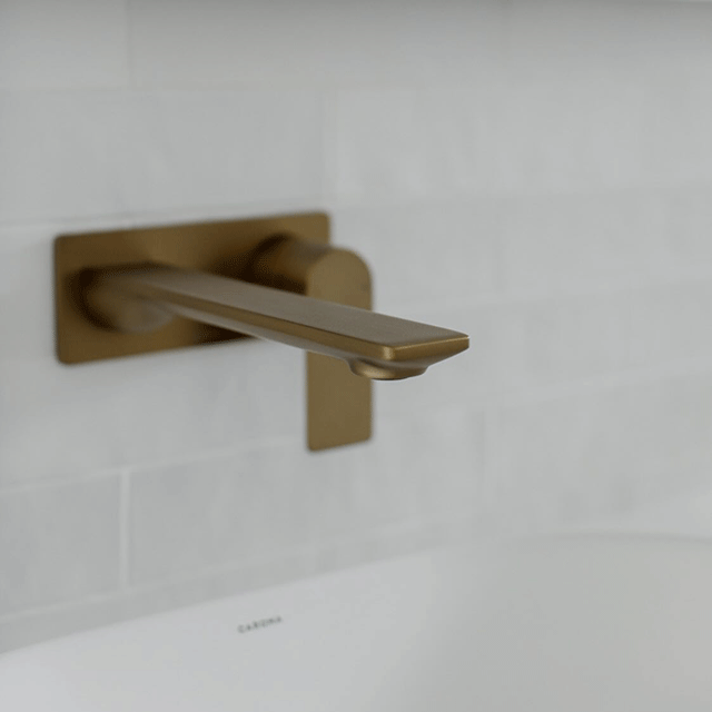 Caroma Contura II brushed brass wall basin/bath mixer tap, wall mounted over a white basin