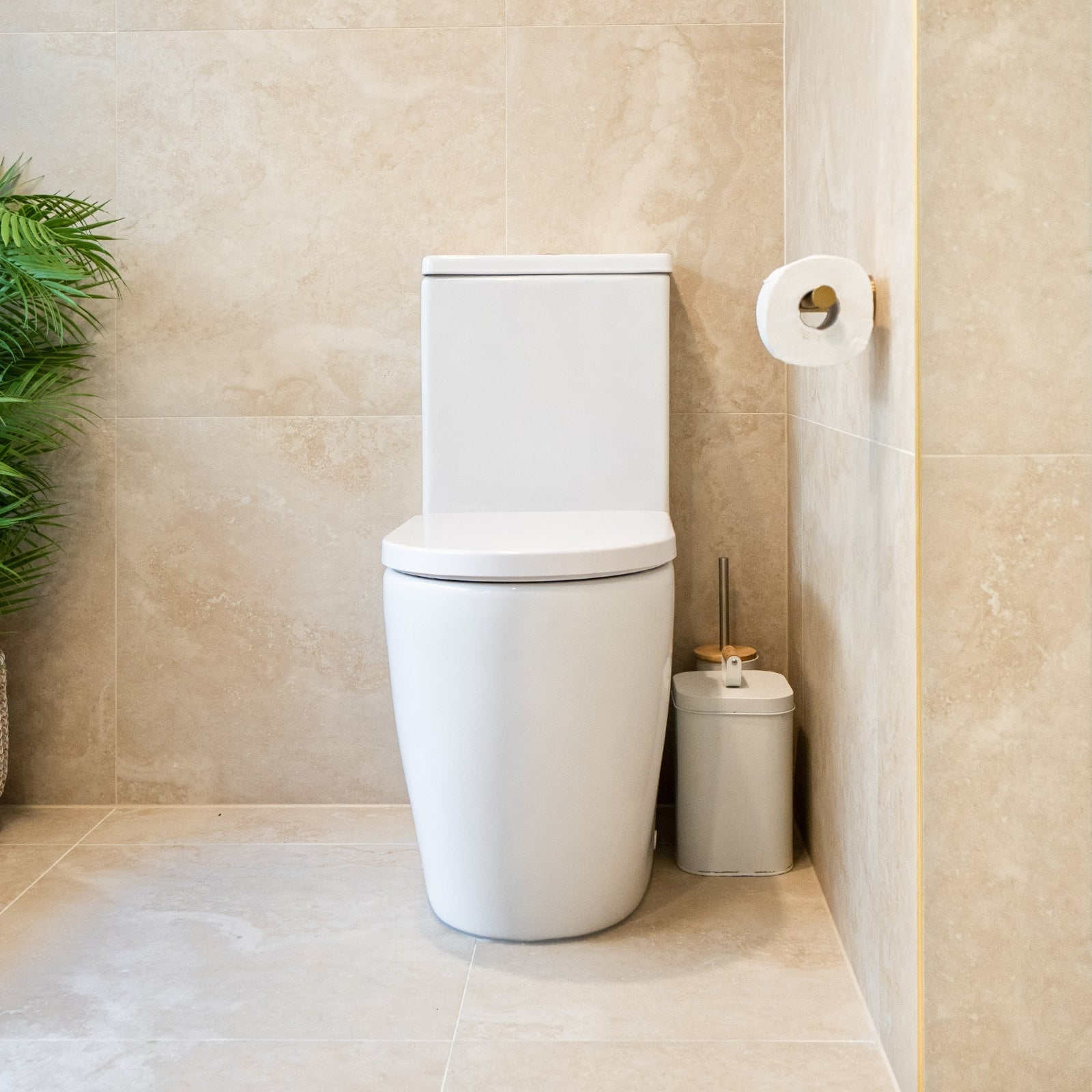 Caroma Urbane II white back to wall toilet suite in a tiled bathroom, front view with matching brush holder