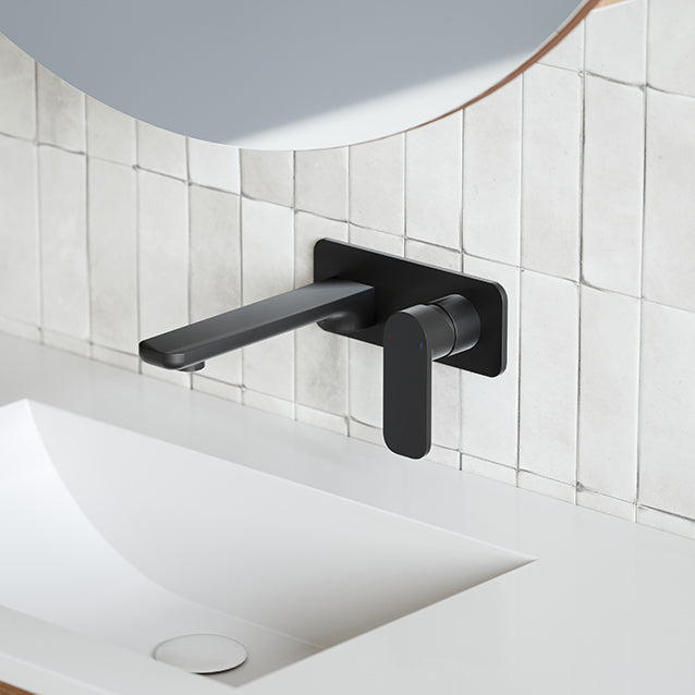 Caroma Luna black wall-mounted basin/bath mixer set above a white basin and tiled wall