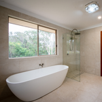 Modern bathroom with brushed nickel Caroma twin shower, frameless glass screen and oval freestanding bath