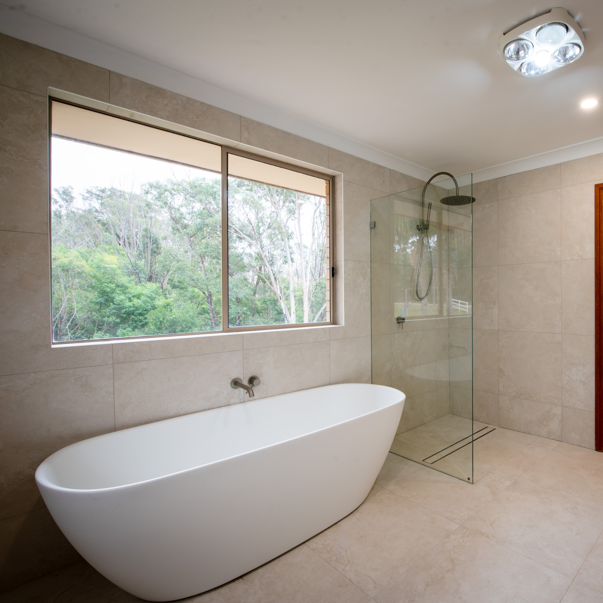 Modern bathroom with brushed nickel Caroma twin shower, frameless glass screen and oval freestanding bath