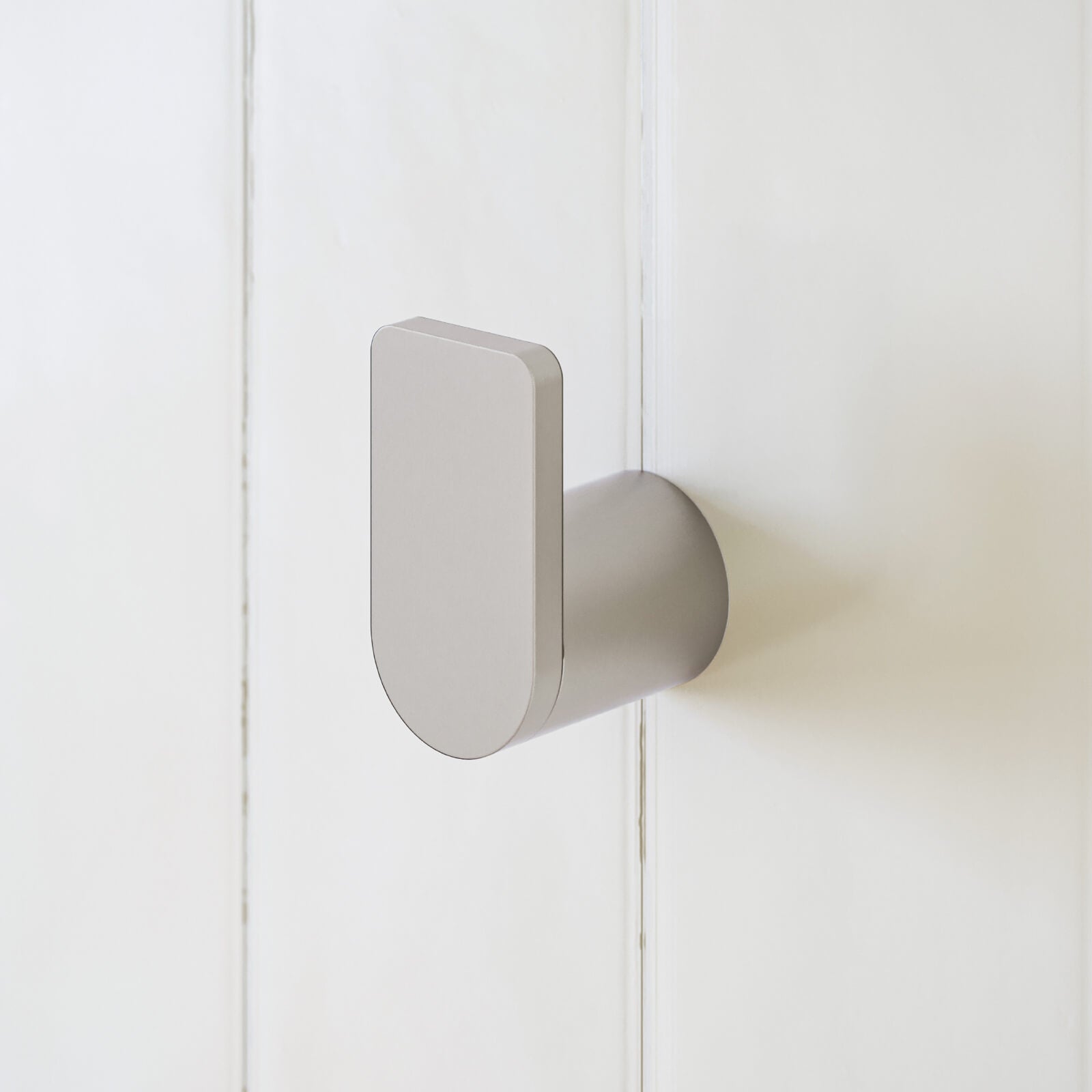 Caroma Urbane II brushed nickel robe hook on a white bathroom wall, front view close-up