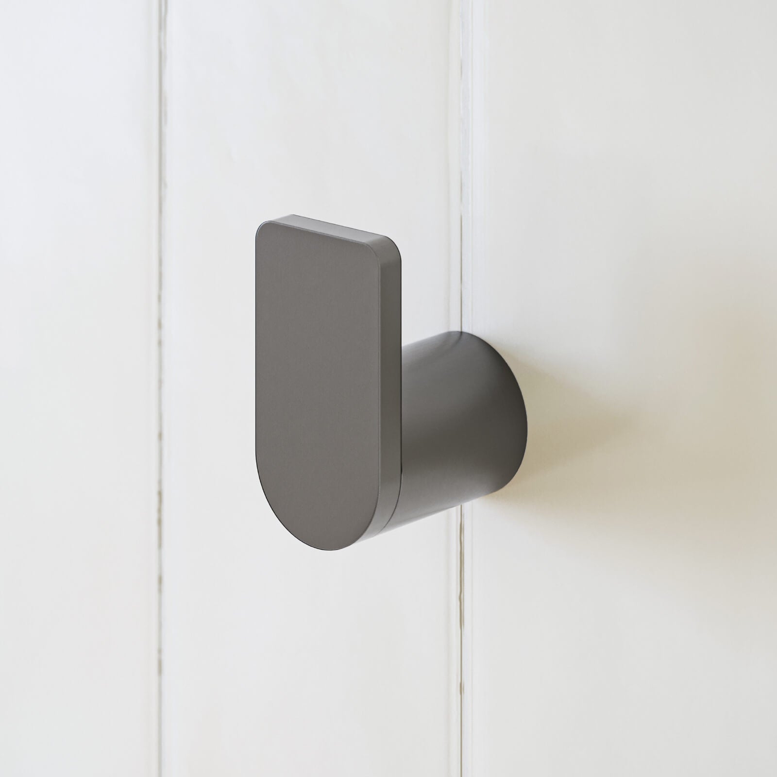 Caroma Urbane II gunmetal robe hook on white bathroom wall, close-up showing rounded rectangular profile and cylindrical base