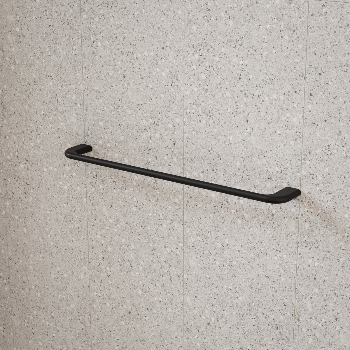 Caroma Contura II single towel rail in matte black, wall-mounted on light speckled bathroom tiles