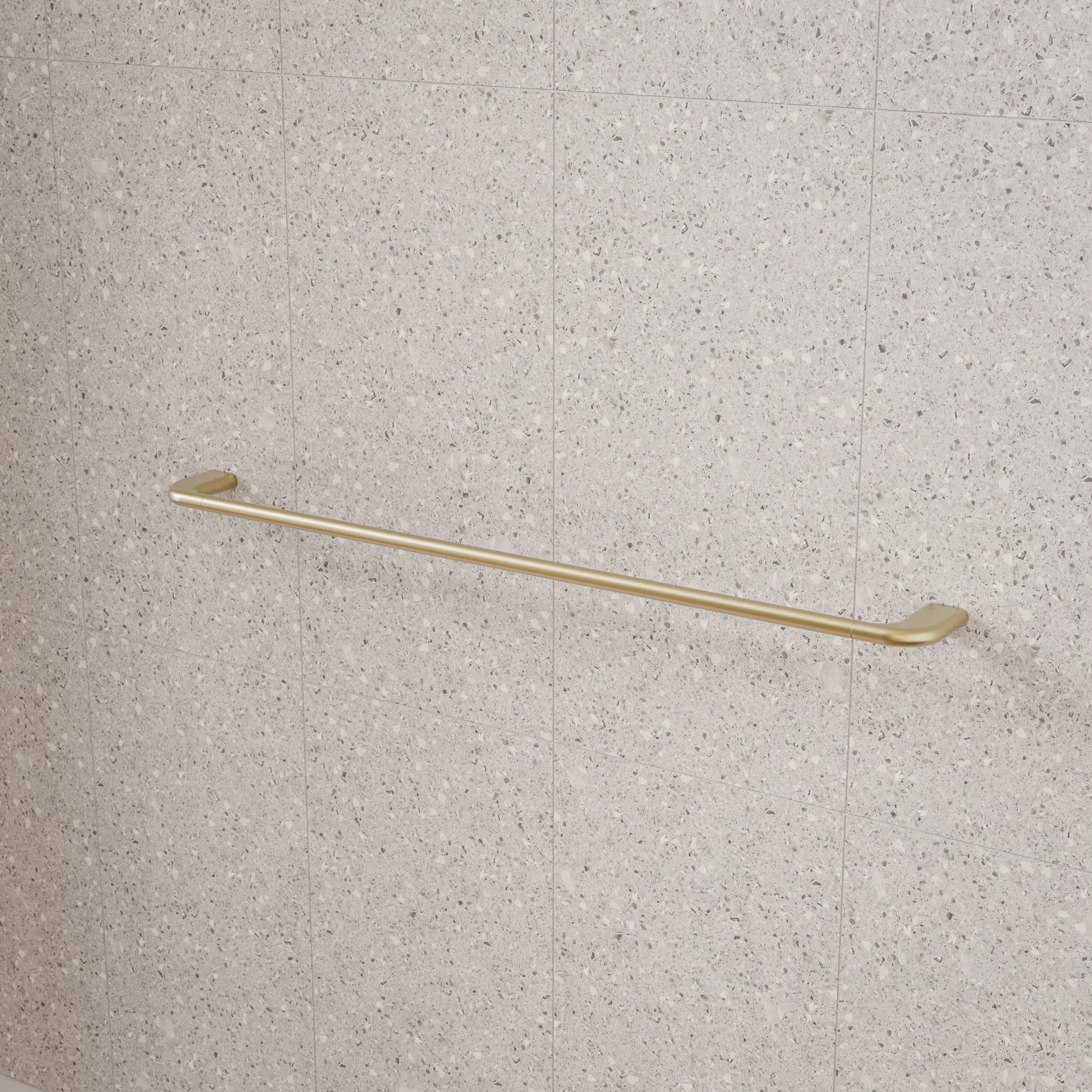 Caroma Contura II single towel rail in brushed brass, wall-mounted against a light stone-tiled bathroom wall