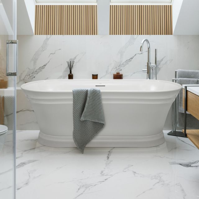 Decina Regent white freestanding oval bath with integrated overflow, shown in a modern bathroom with centre tapware recess and towel.