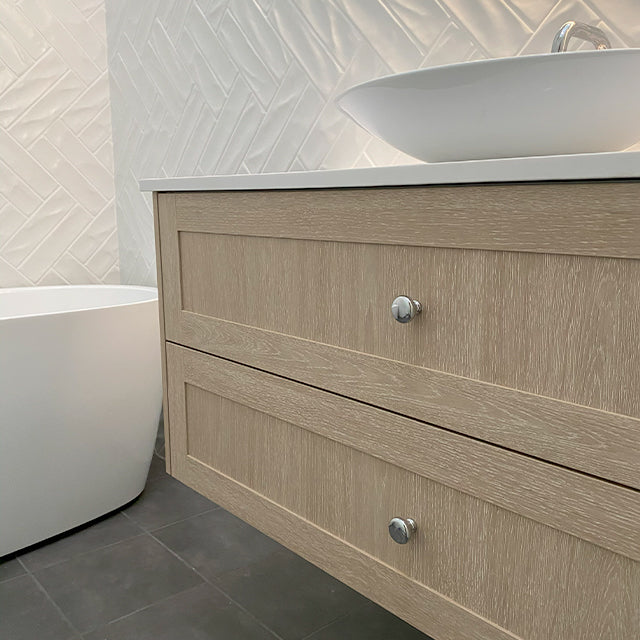 Marquis Pier wall hung vanity in natural oak woodgrain with drawer fronts and white top in bathroom setting