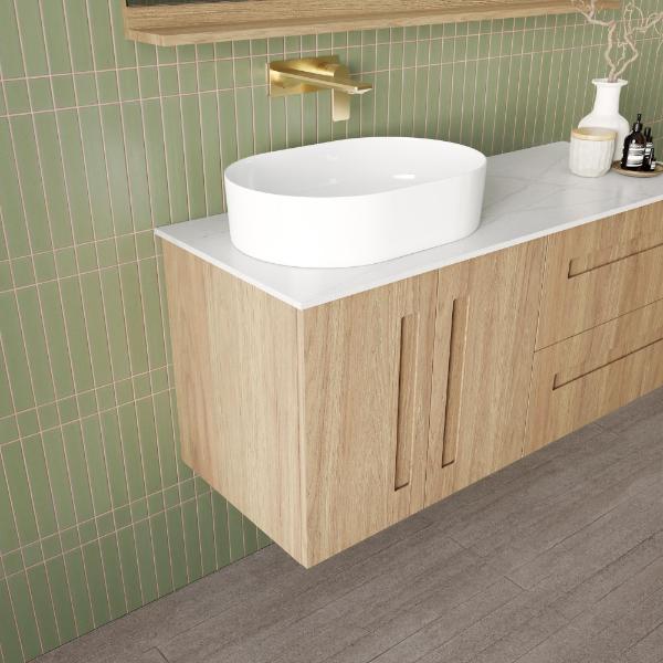 Marquis Gold wall hung vanity in natural oak, with white above-counter basin and marble-look top in bathroom setting