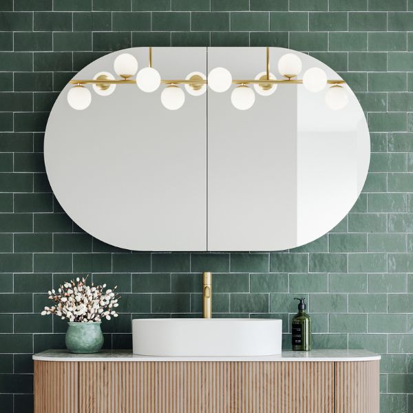 Ingrain Ash horizontal pill shaving cabinet with mirrored doors, shown above a bathroom vanity in a green tiled setting