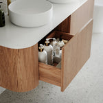 Ingrain curved fluted wall hung vanity in woodgrain finish with white top and open drawer in bathroom setting