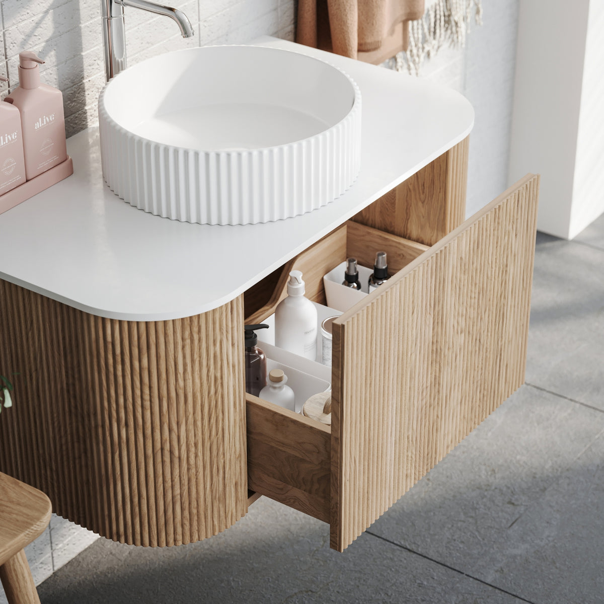Ingrain curved fluted wall hung vanity with white top, woodgrain finish and open drawer in bathroom setting