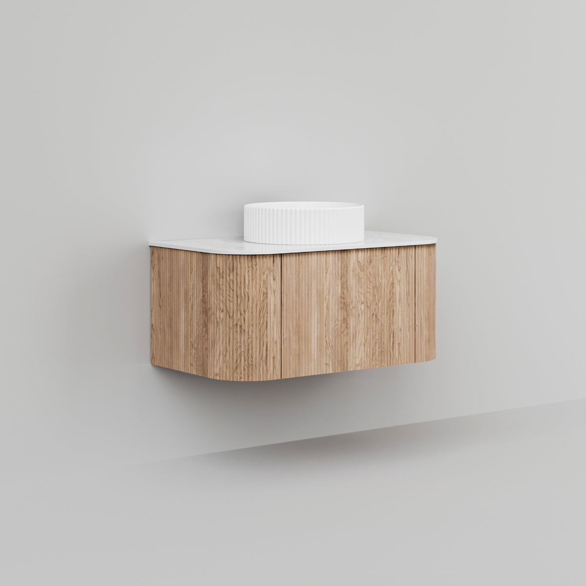 Ingrain Curved Fluted wall hung vanity, woodgrain finish with white top, shown floating in a minimalist bathroom setting