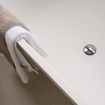 Chrome bath pop-up waste in a white bath, with a towel draped over the edge