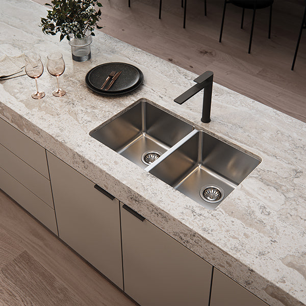 Phoenix 2000 Series double bowl stainless steel kitchen sink inset in stone benchtop with black mixer tap, angled view