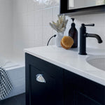 Phoenix Cromford matte black basin mixer on a white vanity, side view in a modern bathroom.