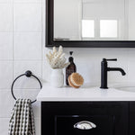 Phoenix Cromford matte black basin mixer on a white vanity, shown in a bathroom setting with mirror and accessories