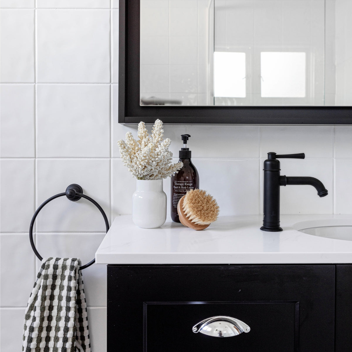 Phoenix Cromford matte black basin mixer on a white vanity, shown in a bathroom setting with mirror and accessories