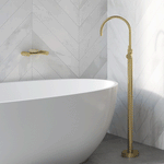 Phoenix Vivid Slimline brushed gold floor-mounted bath mixer beside a freestanding oval bath