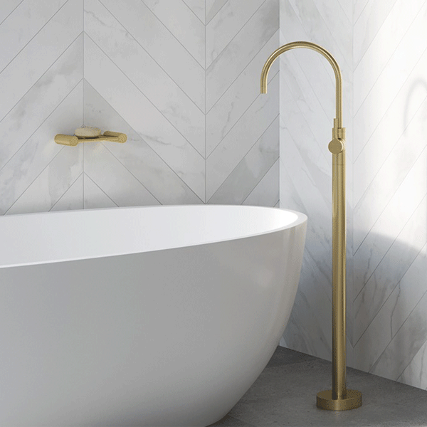 Phoenix Vivid Slimline brushed gold floor-mounted bath mixer beside a freestanding oval bath