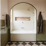 Brushed nickel heated towel ladder with 5 bars mounted in a bathroom beside a shower and bath, shown in a lifestyle setting