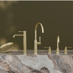 Phoenix Wiltern brushed gold vessel mixer range on a stone benchtop, featuring tall mixer tap and matching accessories