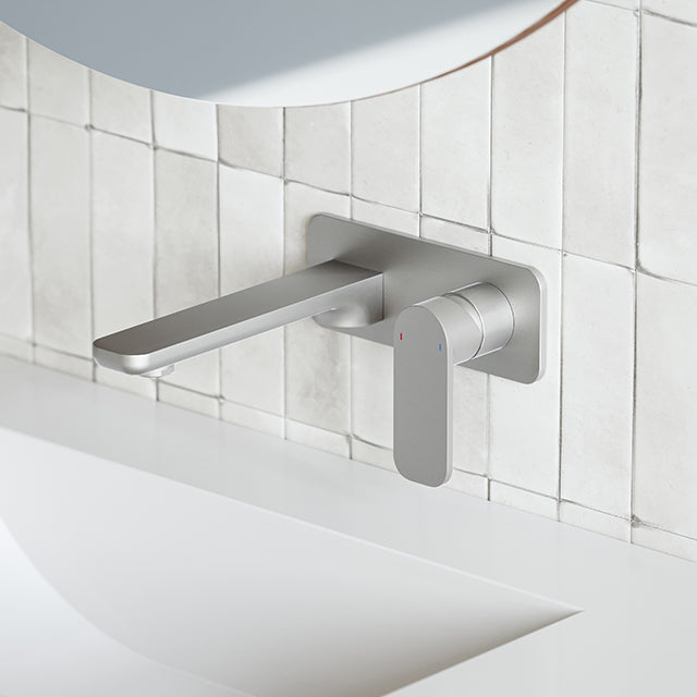 Caroma Luna wall basin/bath mixer in brushed nickel, wall-mounted over a white tiled basin area