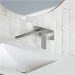 Caroma Luna wall basin mixer in brushed nickel, wall-mounted above a white basin in a modern tiled bathroom