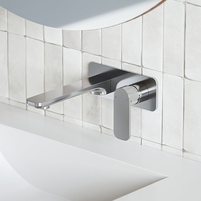 Caroma Luna chrome wall basin/bath mixer with flat spout and paddle handle, mounted above a white basin and tiled wall