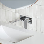 Caroma Luna chrome wall basin/bath mixer set above a white basin, with rounded wall plate and paddle handle