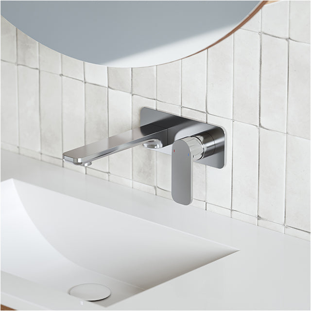 Caroma Luna chrome wall basin/bath mixer set above a white basin, with rounded wall plate and paddle handle