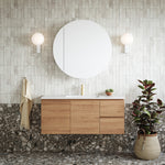 Caroma Luna black basin mixer on a timber vanity in a modern bathroom, front view with round mirror and wall lights