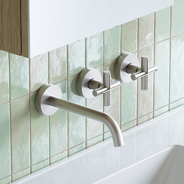 Phoenix Vivid Slimline Plus wall basin/bath set in brushed nickel, with wall-mounted spout and two cross handles against green tiles