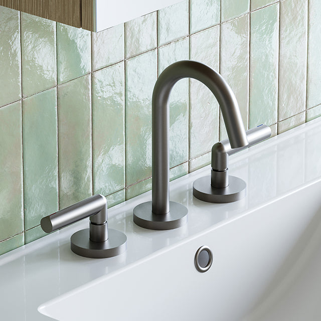 Phoenix Vivid Slimline Plus 3 piece basin set in brushed carbon, with lever handles and round base on a white basin edge.