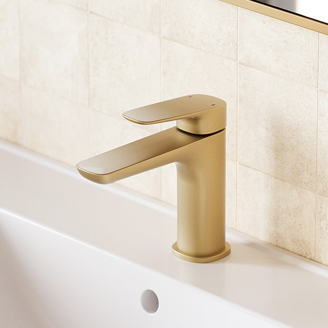 Caroma Contura II basin mixer in brushed brass, hob mounted on a white basin against tiled wall