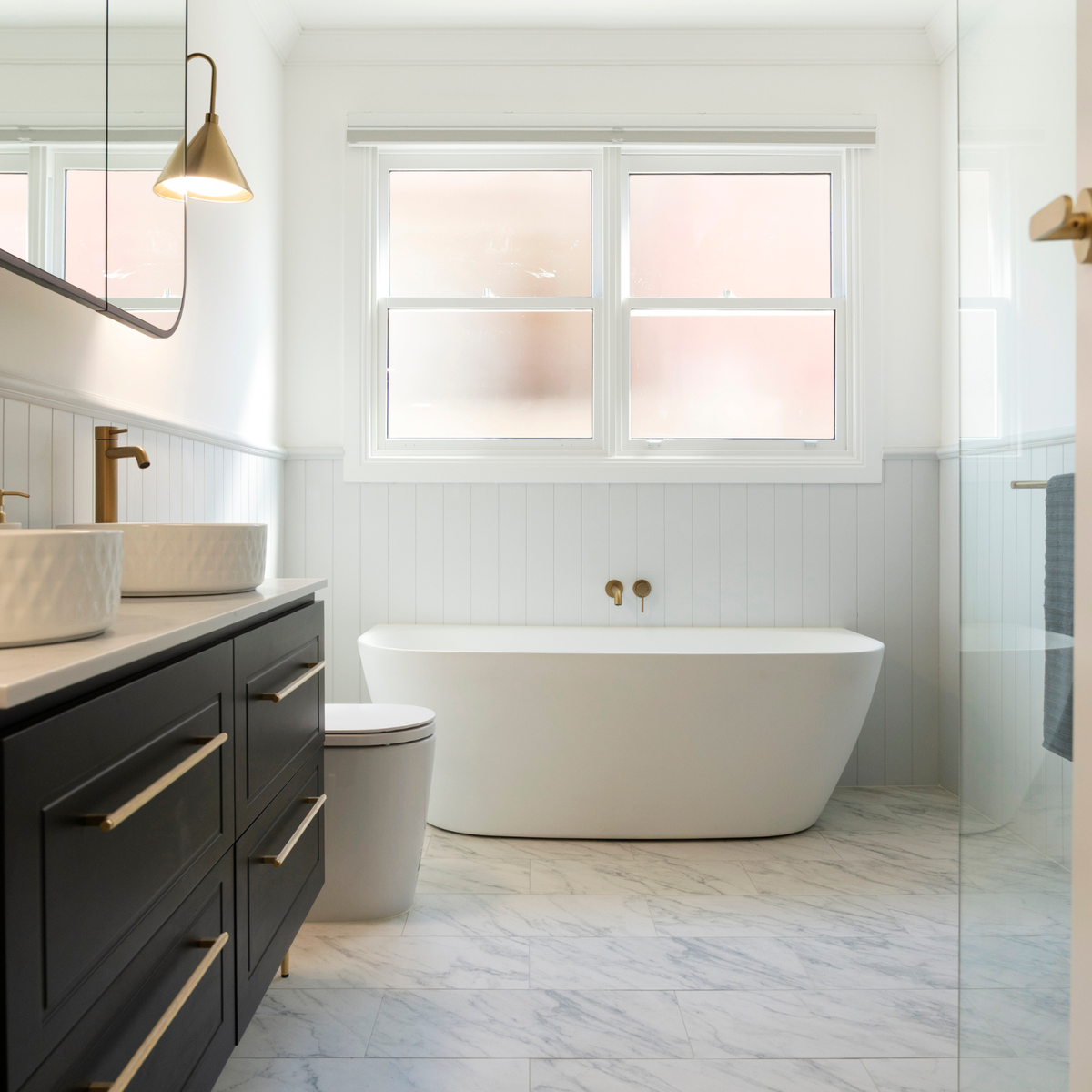 Caroma Contura II matte white back to wall freestanding bath in a modern bathroom, oval profile with wall-mounted tapware