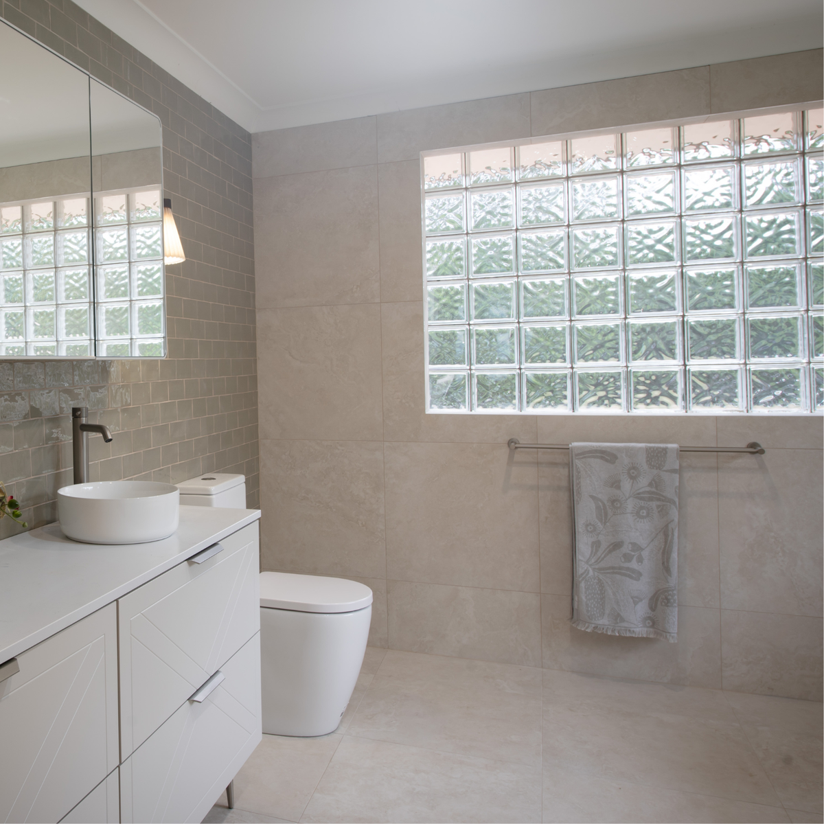 Caroma Liano II double towel rail in brushed nickel, mounted on a tiled bathroom wall with a towel hanging
