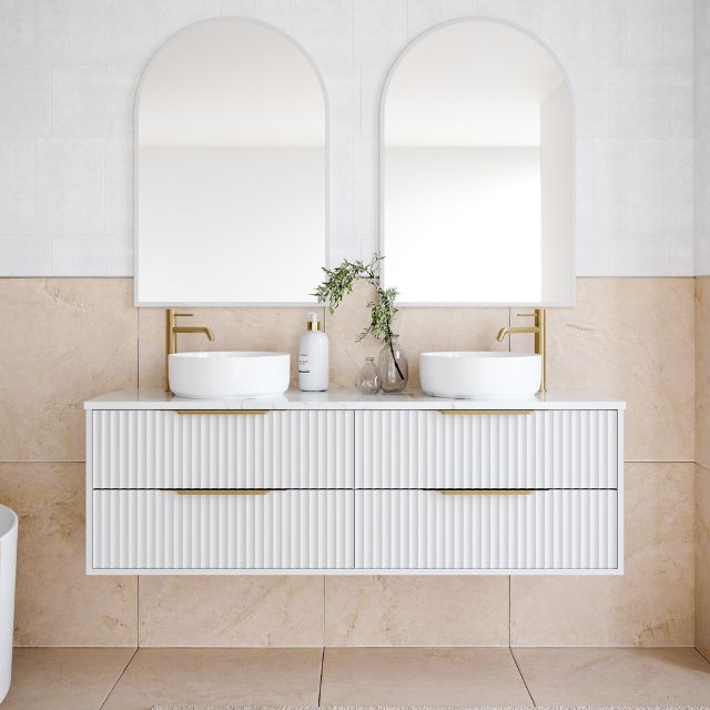 Timberline Emmett Apollo wall hung vanity in white with fluted drawers, above counter basins and arched mirrors in a bathroom.