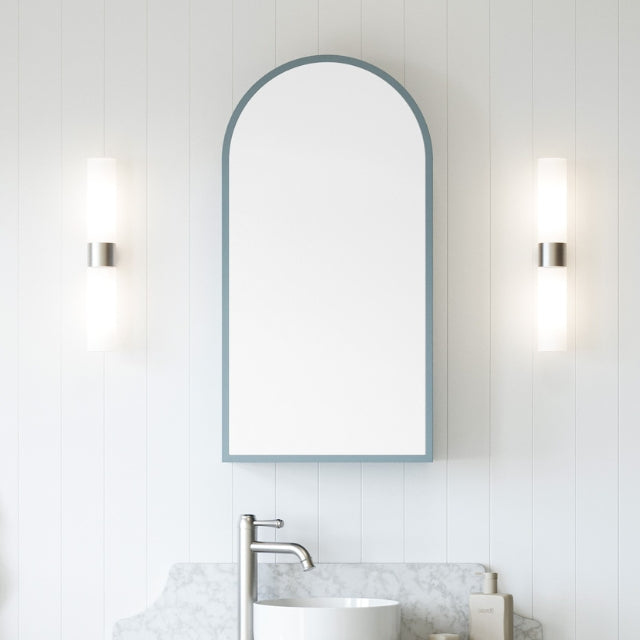 Timberline Church Frame shaving cabinet with arched mirrored door in muted blue, above a bathroom vanity