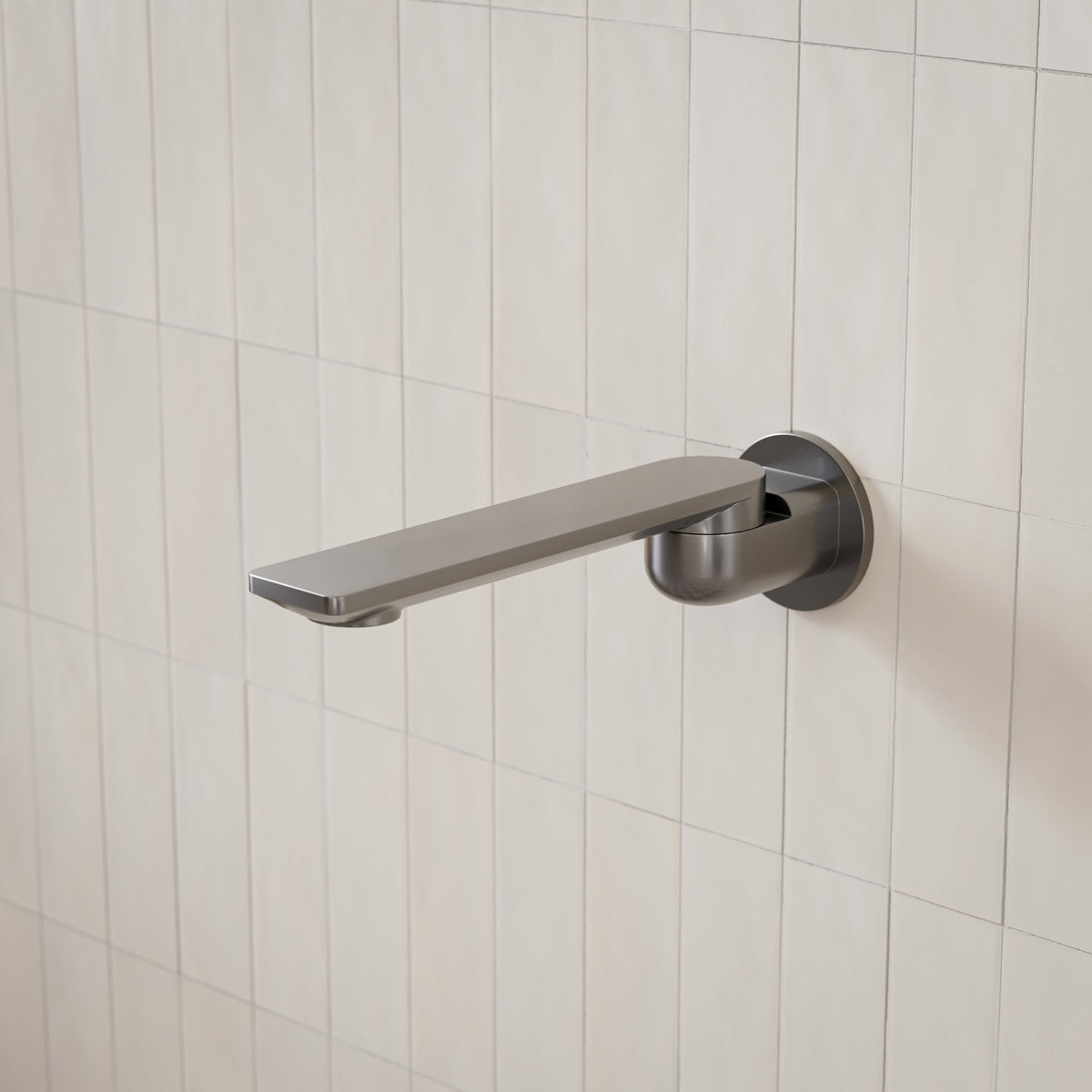 Caroma Urbane II round wall-mounted bath spout in gunmetal finish, shown against white tiled wall at side angle