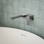 Caroma Urbane II wall-mounted basin/bath mixer in gunmetal, rectangle design, shown over a bath against tiled wall