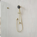 Caroma Urbane II brushed brass rail shower with round handset and hose, mounted on tiled shower wall