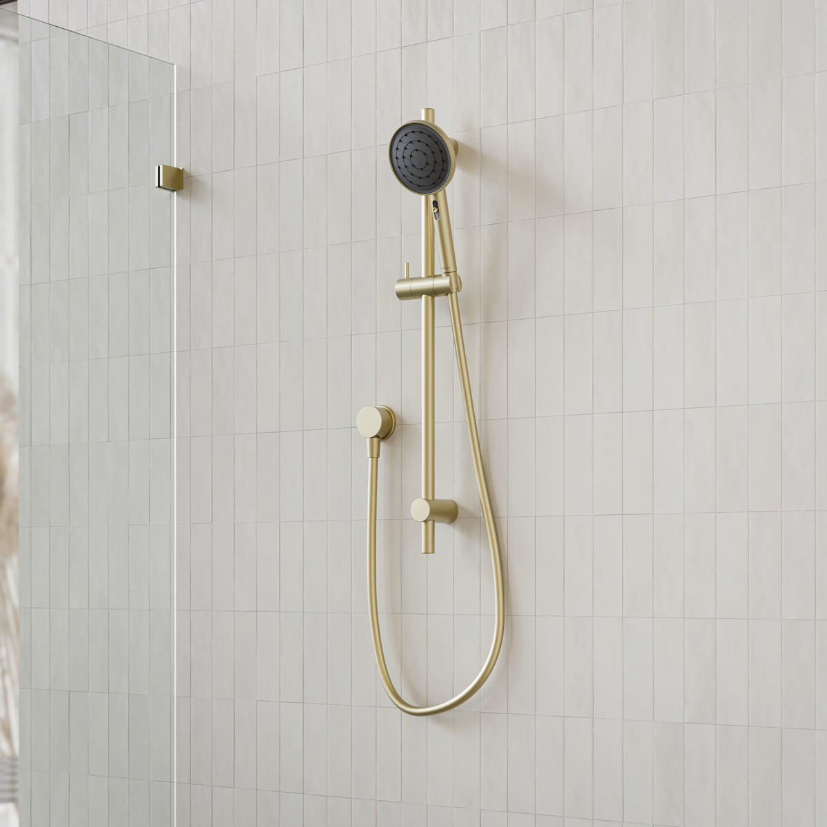 Caroma Urbane II brushed brass rail shower with round handset and hose, mounted on tiled shower wall
