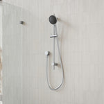 Caroma Urbane II rail shower in brushed nickel, with round handset, hose and wall rail in a tiled bathroom setting