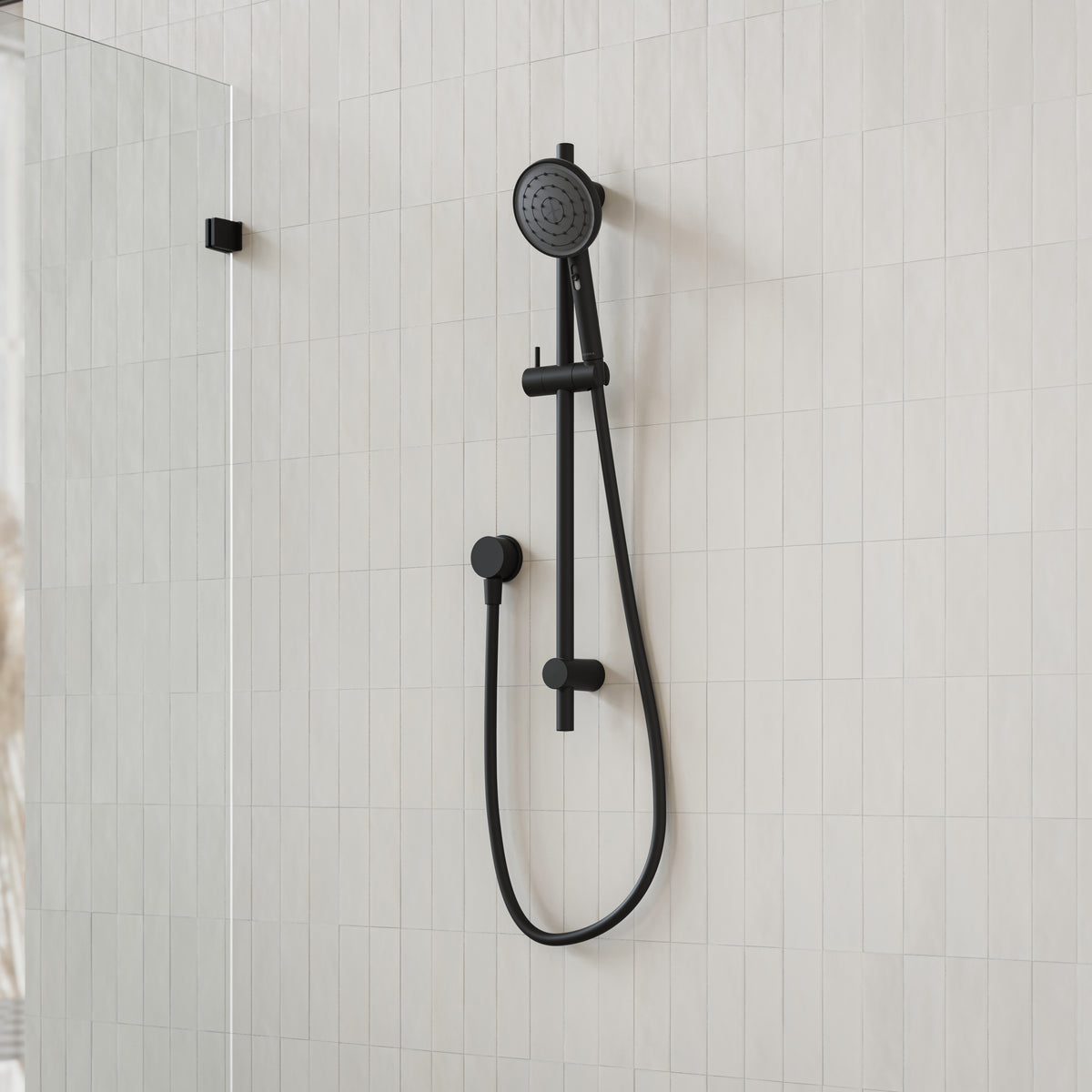 Caroma Urbane II matte black rail shower with round handset on white tiled bathroom wall